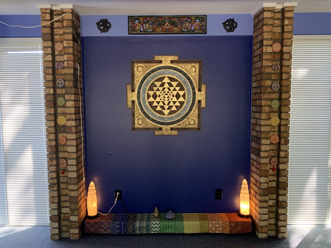 The Painted Lotus altar — a Sri Yantra mandala framed in gold between brick columns, with Himalayan salt lamps glowing on either side